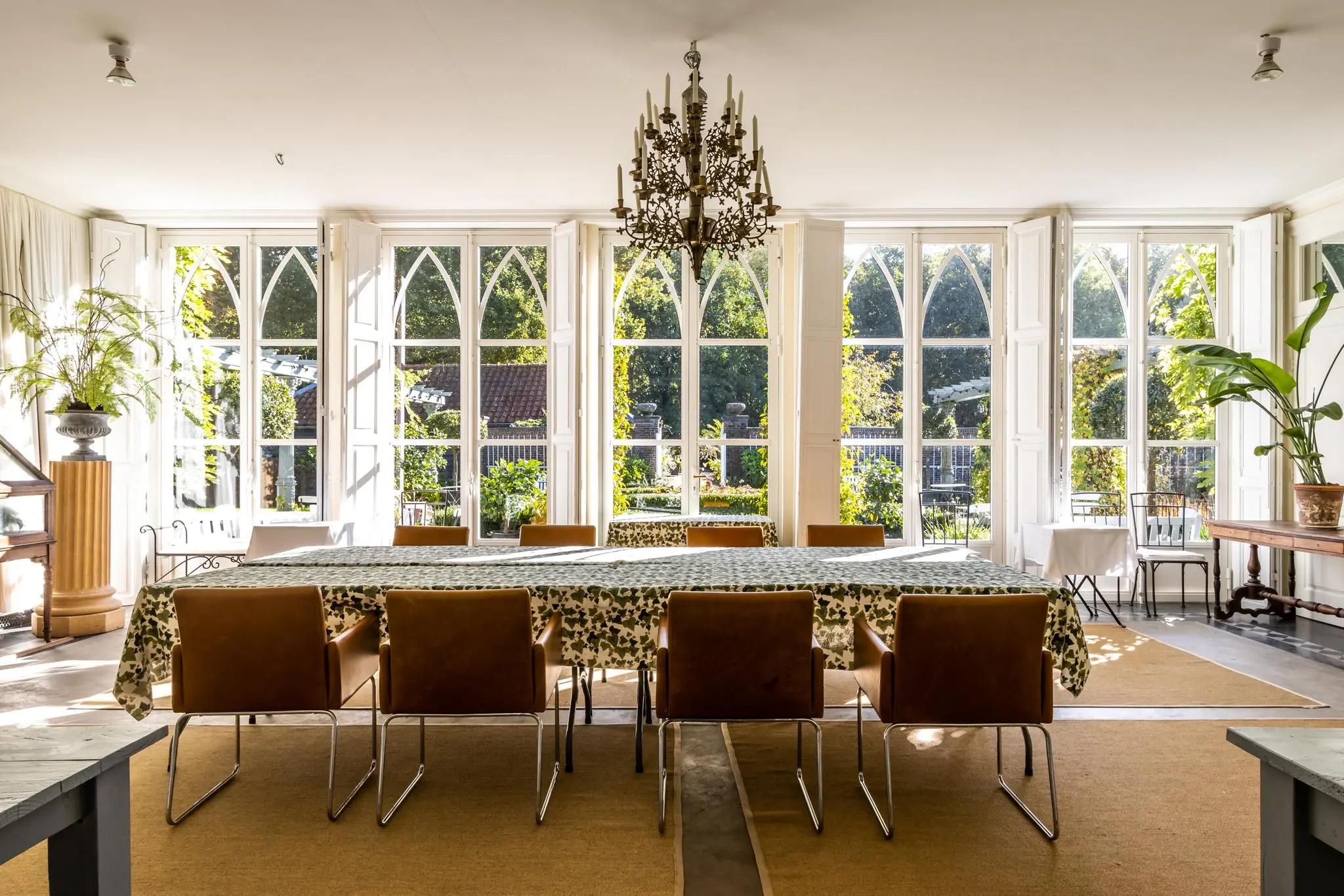 Stijlvolle eetruimte aan de Langbroekerdijk met grote ramen, een lange tafel met bladmotief en uitzicht op een groene tuin.
